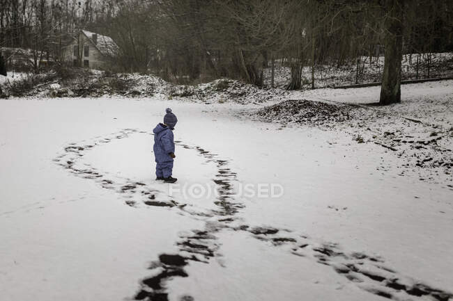 Small boy in blue winter clothes onesie standing in a circle mad — Stock Photo