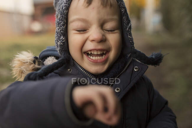 Ridere e correre bambino ragazzo in abiti caldi in cortile — Foto stock