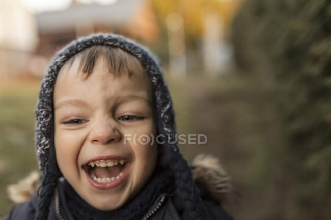 Riéndose y corriendo niño en ropa de abrigo en el patio trasero - foto de stock