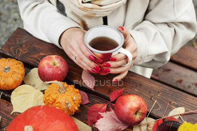 Осінню композицію з чашкою чаю та яблук на дерев'яному столі. Жінка п'є чай — стокове фото