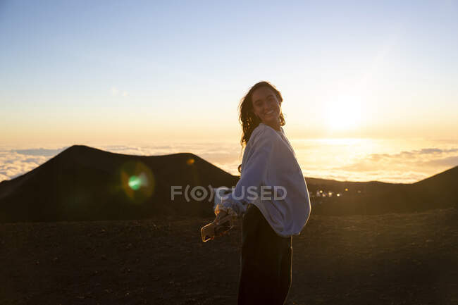 Молодая женщина в платье с рюкзаком на фоне заката — стоковое фото