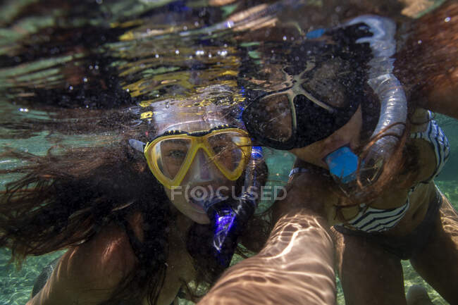 Foto submarina de una joven en un vestido rojo con una máscara en el agua - foto de stock