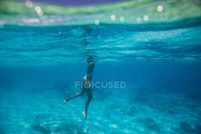 Jeune femme en bikini bleu nageant dans l'eau — Photo de stock