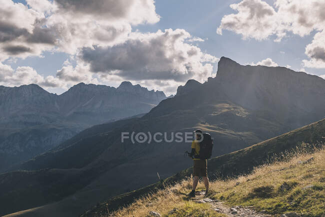 Man wearing a backpack and admiring the high mountains against cloudy sky, Pyrenees, Aragon, Spain — Stock Photo