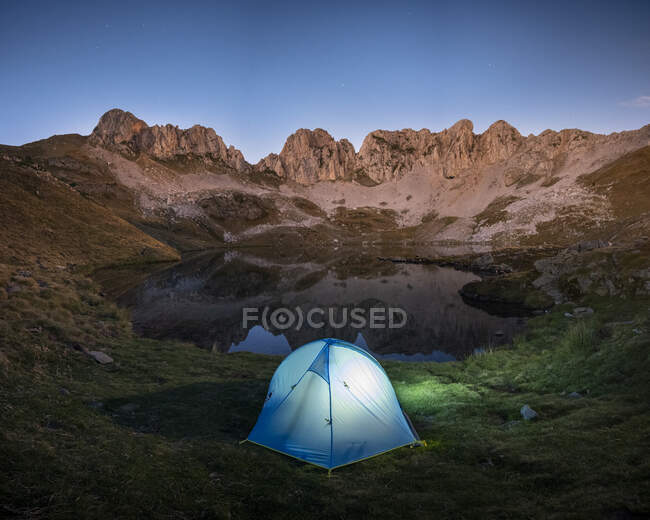 Tienda contra el lago y la escena de la montaña antes de la noche, Pirineos - foto de stock