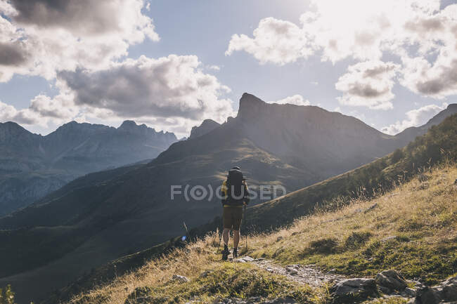 Mann wandert mit Rucksack gegen hohe Berggipfel und bewölkten Himmel, Pyrenäen, Aragon, Spanien — Stockfoto