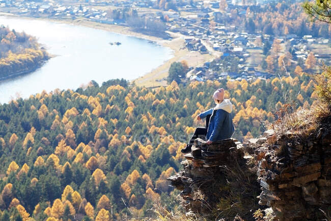 Жіноча туристка сидить на стрімкій скелі на березі річки Іркут. — стокове фото