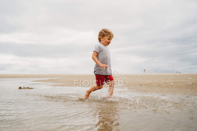 Niño jugando en la arena en la playa - foto de stock