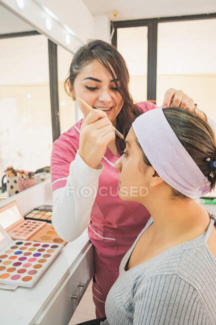Jovem mulher se preparando para colocar maquiagem para um evento especial. Em um centro de maquiagem aproveitando este dia. — Fotografia de Stock