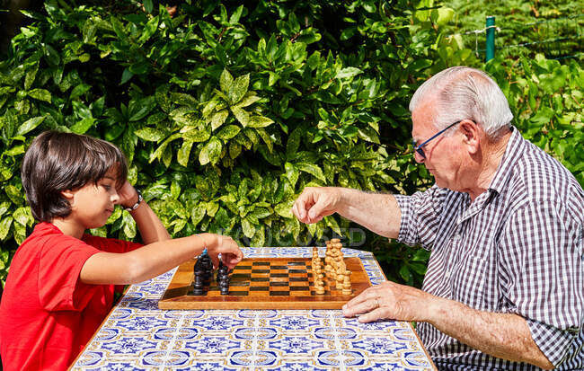 Abuelo y nieto sobre tablero de ajedrez - foto de stock