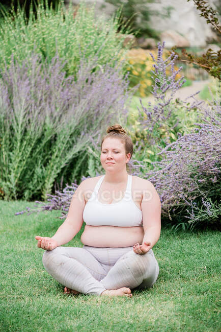 Porträt einer erwachsenen kurvigen Frau in Sportbekleidung, die Yoga im Garten praktiziert — Stockfoto