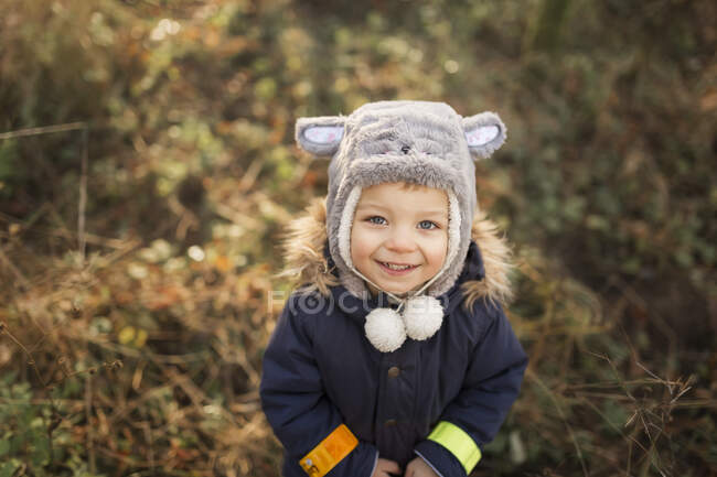 Piccolo ragazzo felice nella foresta in piedi e guardando in alto — Foto stock