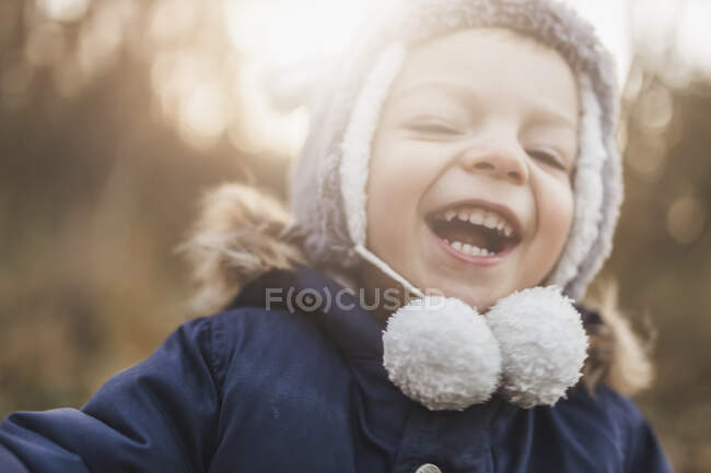 Tête de petit garçon riant dans la forêt en chapeau d'hiver — Photo de stock