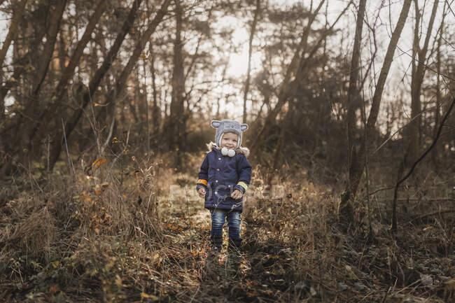 Маленький счастливый мальчик, стоящий в лесу осенью — стоковое фото