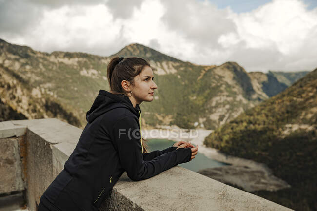 Giovane donna seduta sulla roccia e guardando la distanza — Foto stock