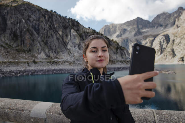 Jovem mulher sentada no lago de montanha em montanhas — Fotografia de Stock
