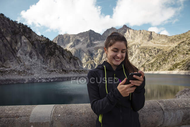 Jovem mulher sentada no lago e gosta da montanha. — Fotografia de Stock