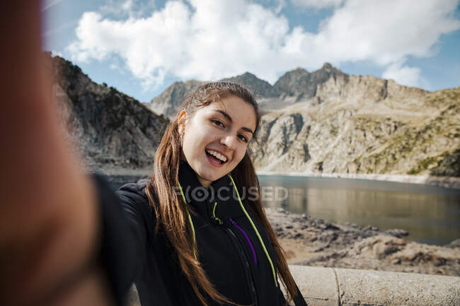 Young woman with backpack and trekking poles on the mountain — Stock Photo