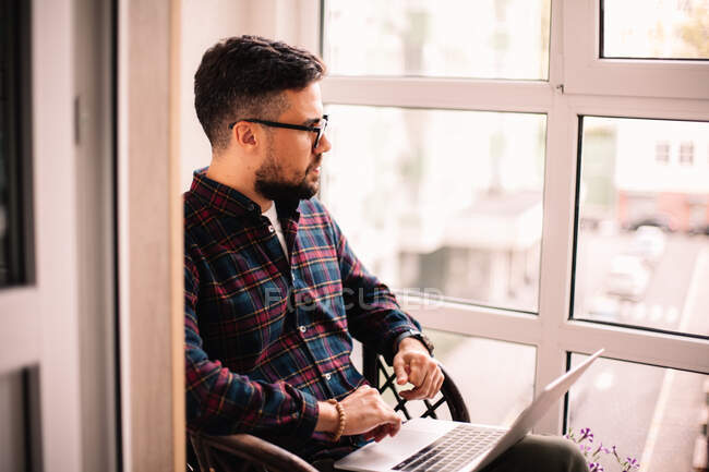 Serious thoughtful man using laptop computer at home — Stock Photo