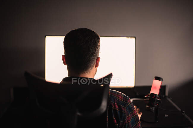 Visão traseira do homem sentado na mesa trabalhando no computador — Fotografia de Stock
