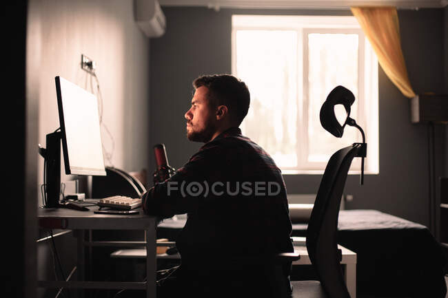 Чоловік сидить за столом, працює на комп'ютері вдома — стокове фото