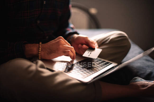 Hombre usando la tarjeta de crédito y ordenador portátil de compras en línea en casa - foto de stock