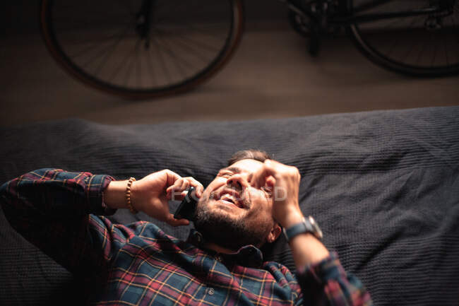 Uomo felice che parla sul telefono intelligente sdraiato sul letto a casa — Foto stock
