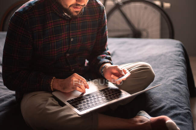 Homme utilisant la carte de crédit et ordinateur portable achats en ligne à la maison — Photo de stock