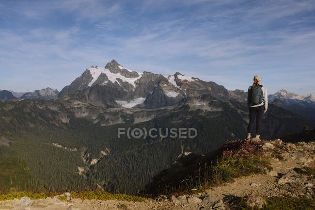 Excursionista con una mochila y una montaña en el fondo - foto de stock