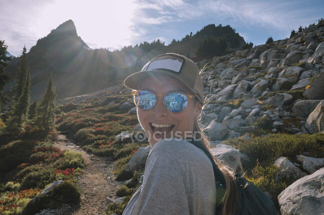Жінка з рюкзаком і сонцезахисними окулярами на фоні гір — стокове фото
