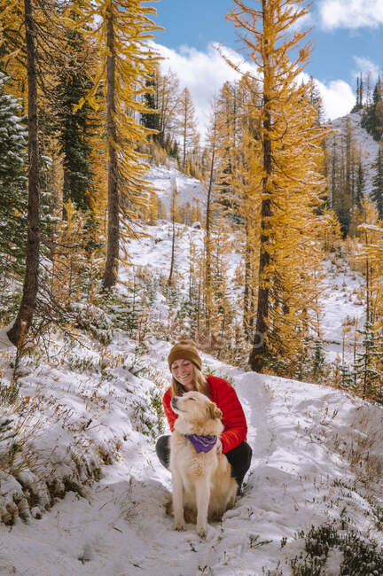 Hermosa chica en el bosque de invierno con un perro. - foto de stock