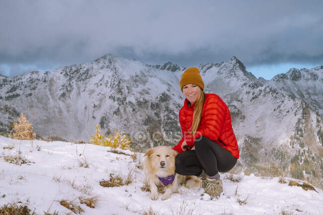 Mujer joven en la nieve con el perro beagle y su mascota. - foto de stock