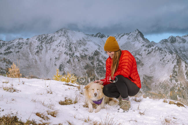 Собака со своим хозяином в зимних горах на снегу — стоковое фото