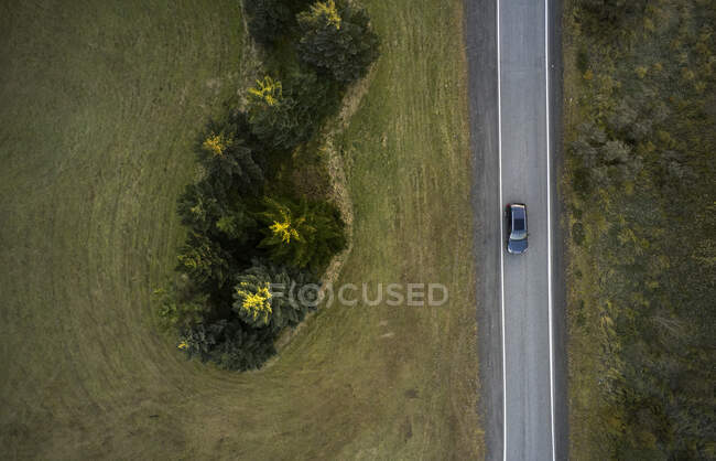 Blick von oben auf Auto, das auf asphaltierter Fahrbahn zwischen Wald und Feld in ländlichem Gelände in Island fährt — Stockfoto