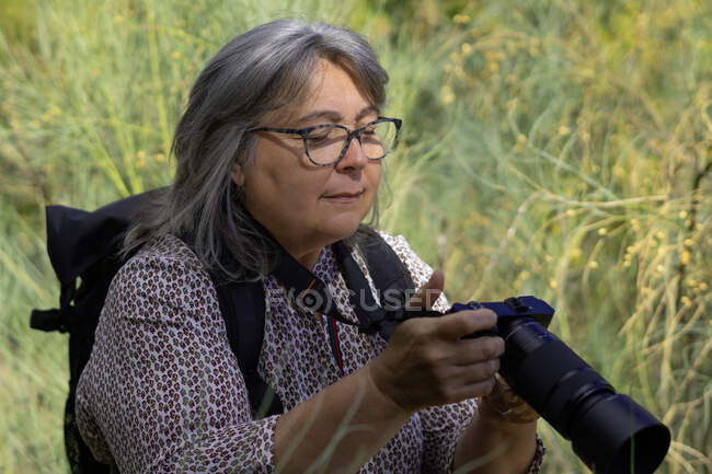 Ältere weißhaarige Frau beim Fotografieren im Wald — Stockfoto