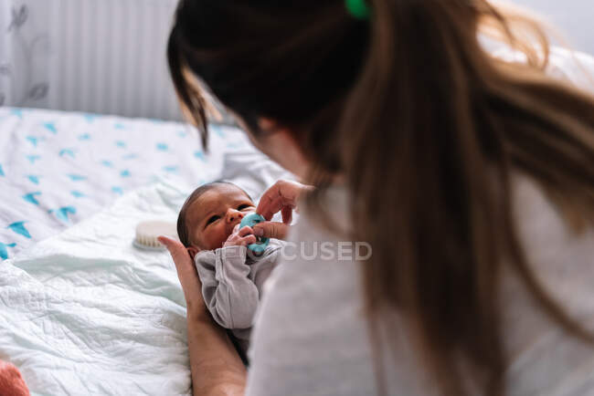 Mother putting pacifier to her baby in bed. — Stock Photo