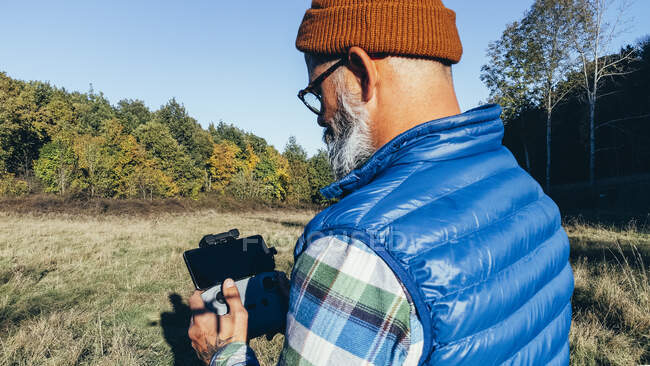 Rear view of a man on the mountain testing his drone and recording — Stock Photo