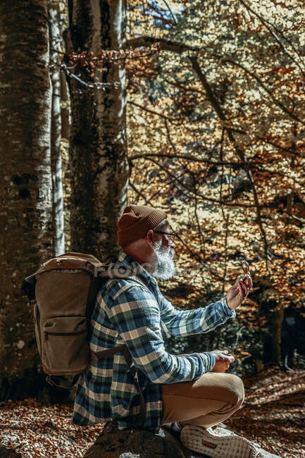 Avventuroso uomo barbuto consulta la sua bussola manuale in un'escursione al tramonto — Foto stock