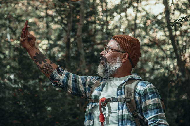 Человек делает селфи во время прогулки по лесу осенью — стоковое фото