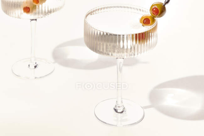 Two cold vodka or gin martini with olives garnish on white background — Stock Photo