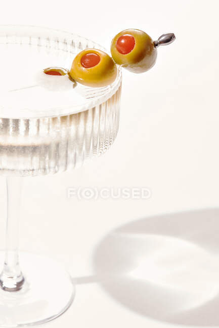 Primer plano de vodka o gin martini con aceitunas sobre fondo blanco - foto de stock