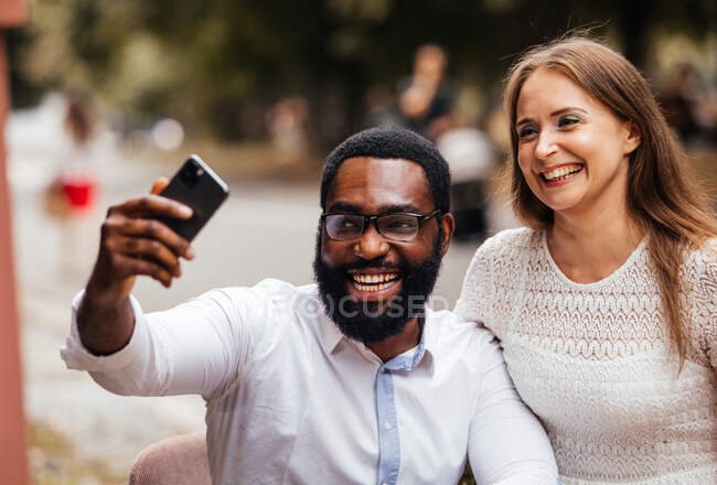 La bella giovane coppia di persone diverse sta scattando una foto in uno smartphone in città — Foto stock
