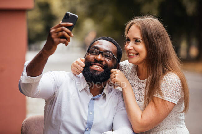 La hermosa pareja joven de diversas personas están tomando una foto en un teléfono inteligente en la ciudad - foto de stock