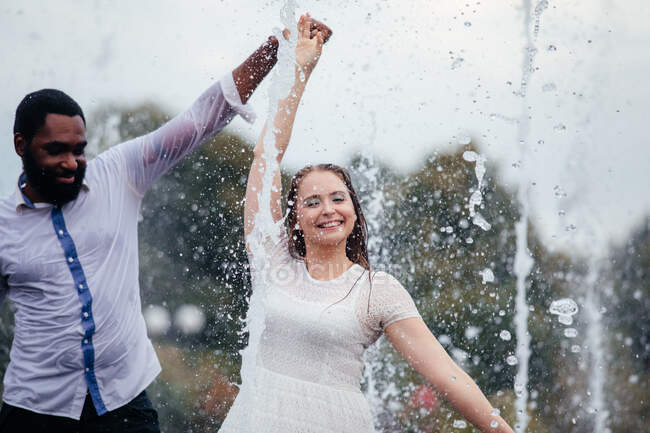 The beautiful young couple of diverse people are dancing together in a city fountain — Stock Photo