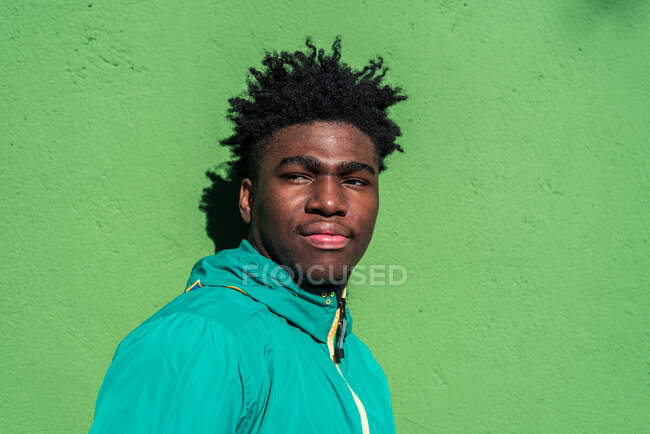 Портрет серйозного чорного хлопчика на фоні зеленої стіни . — стокове фото