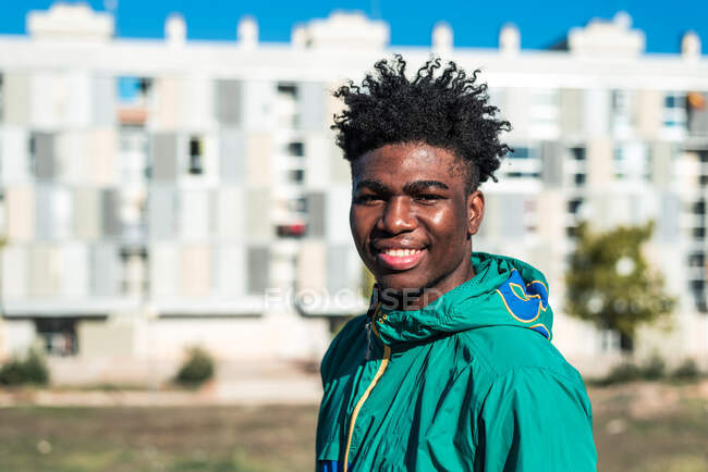 Retrato del chico negro afroamericano sonriendo. Vestido con sudadera verde. - foto de stock