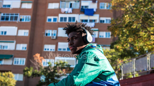 Chico negro afroamericano escuchando música en la ciudad. - foto de stock