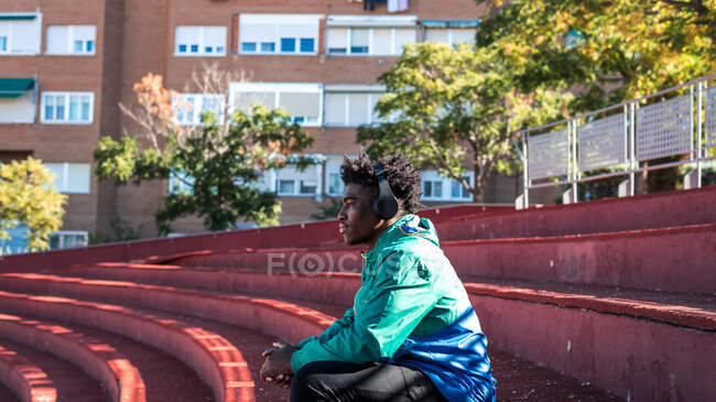 Jeune homme noir se détendre tout en écoutant de la musique dans la ville. — Photo de stock