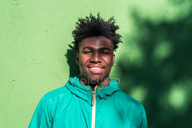 Retrato de sorrindo menino preto no fundo da parede verde. — Fotografia de Stock