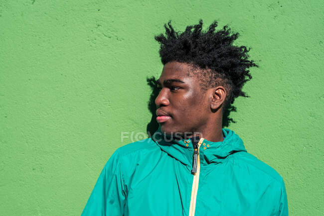 Portrait of serious black boy on green wall background. — Stock Photo